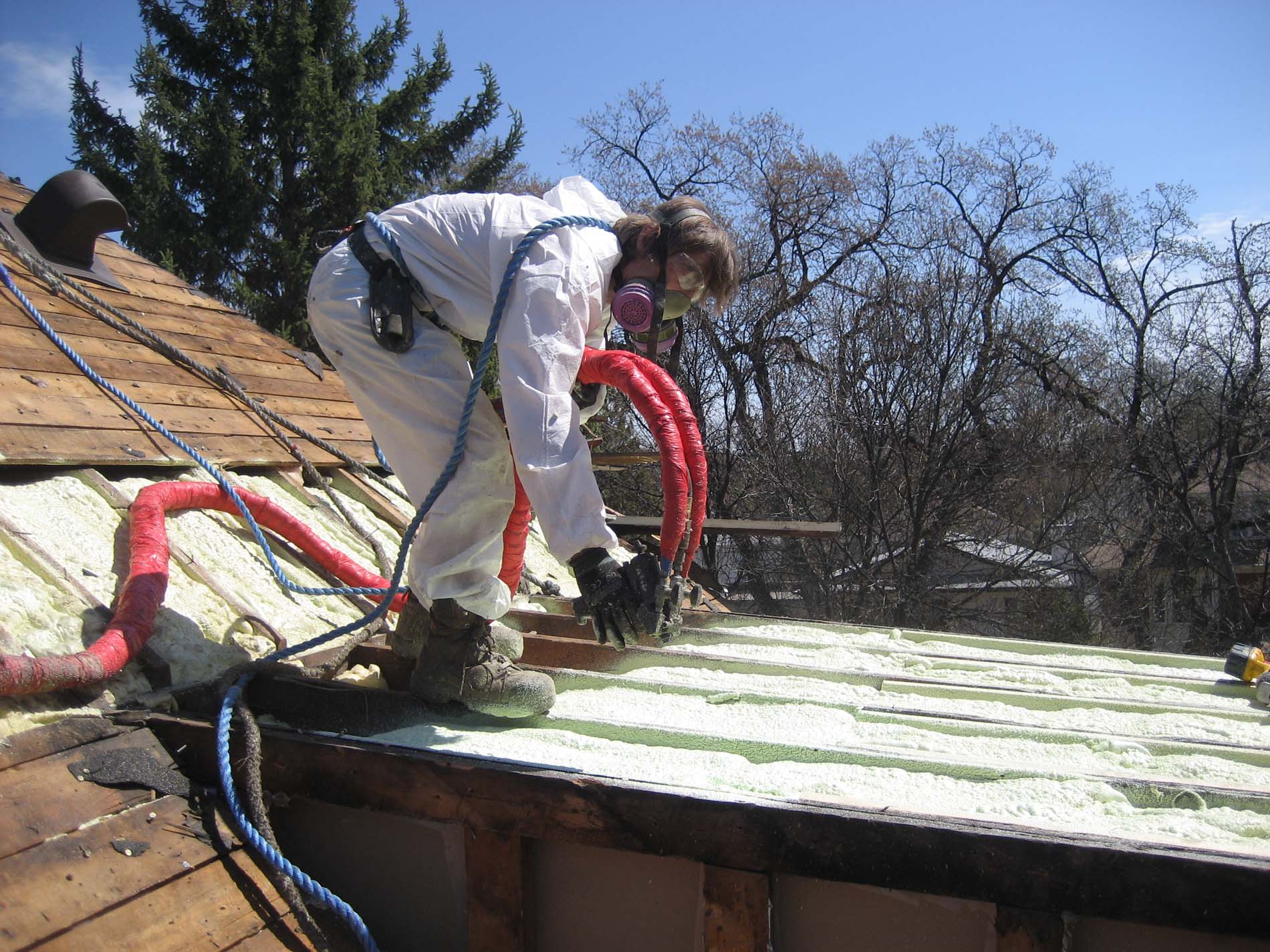 Above All crew applying spray foam insulation on a roof deck